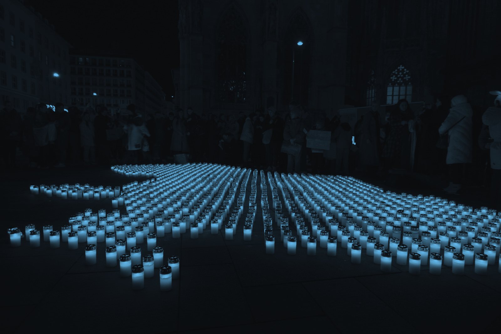 People gathered among candles at night